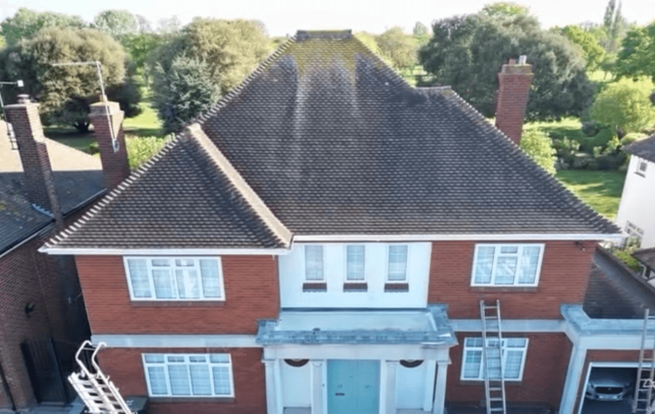Large detached house with dark mossy dirty roof before professional cleaning